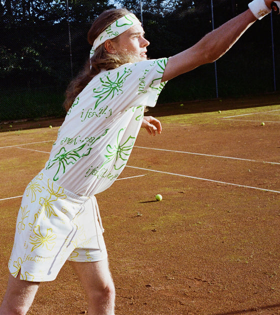 Gen z guy wearing flower print t-shirt and bandana on tennis court